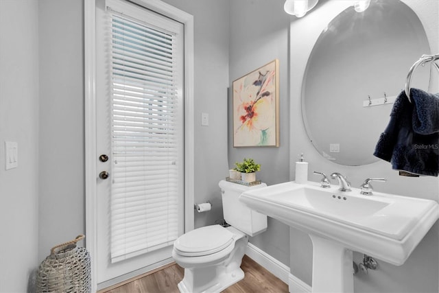 bathroom with wood finished floors, toilet, a sink, and baseboards