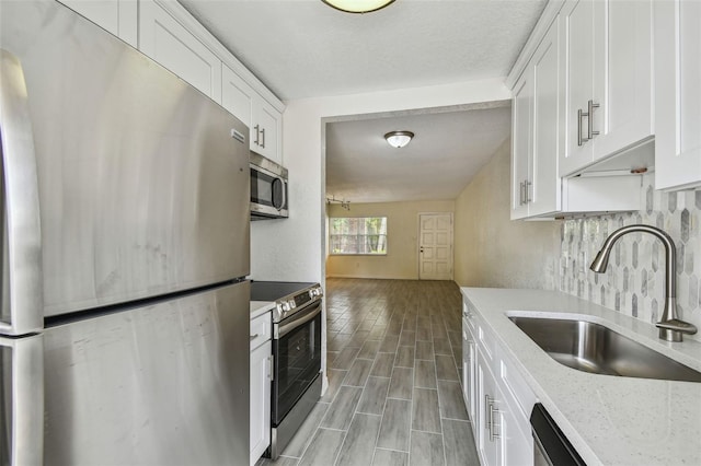 208 Danube Ave Unit 101, Tampa, FL 33606 - kitchen featuring appliances with stainless steel finishes, a sink, white cabinetry, light wood-type flooring, and light stone countertops