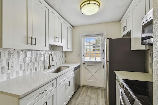 208 Danube Ave Unit 101, Tampa, FL 33606 - kitchen with appliances with stainless steel finishes, a sink, decorative backsplash, and white cabinets