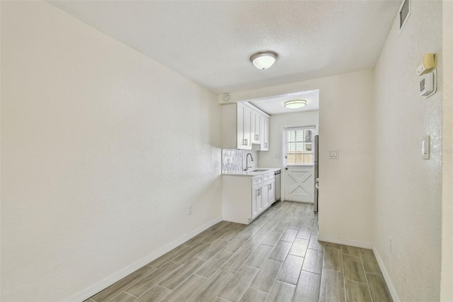 208 Danube Ave Unit 101, Tampa, FL 33606 - kitchen with a sink, stainless steel appliances, light countertops, baseboards, and white cabinetry