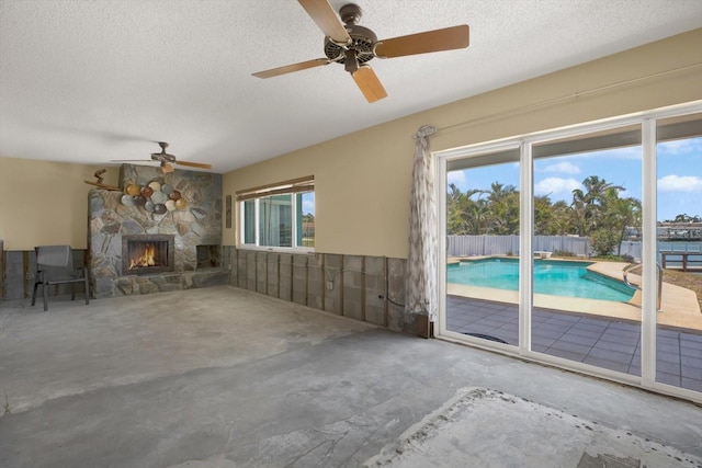 11628 Grove St, Seminole, FL 33772 - unfurnished living room with a textured ceiling, ceiling fan, a fireplace, and unfinished concrete flooring