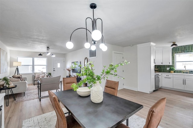 dining space featuring healthy amount of natural light, light wood-style flooring, and baseboards