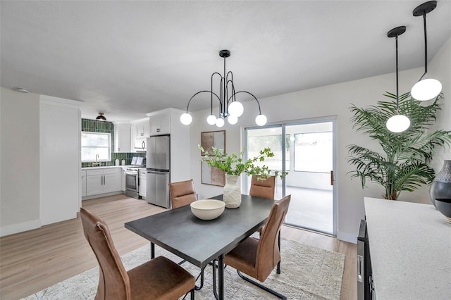 dining room with light wood-style flooring, a chandelier, and baseboards