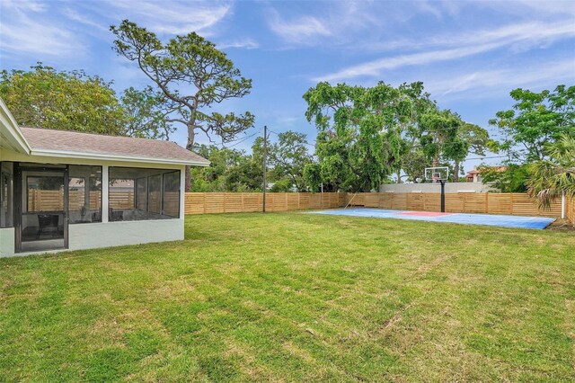 view of yard featuring a sunroom and basketball hoop