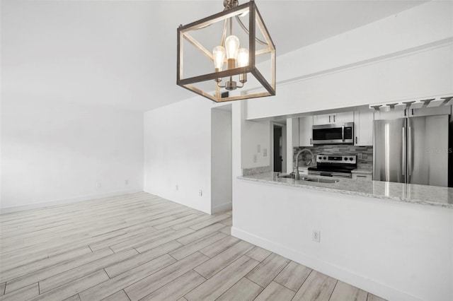 3102 W Horatio St Unit 13, Tampa, FL 33609 - kitchen featuring appliances with stainless steel finishes, a sink, light wood-type flooring, a chandelier, and light stone countertops