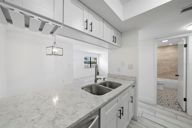 3102 W Horatio St Unit 13, Tampa, FL 33609 - kitchen with a sink, white cabinetry, light stone countertops, and decorative light fixtures