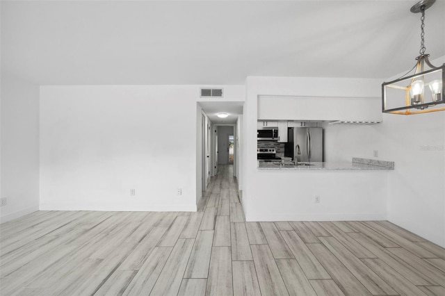 3102 W Horatio St Unit 13, Tampa, FL 33609 - kitchen with appliances with stainless steel finishes, light wood finished floors, light countertops, decorative light fixtures, and a chandelier