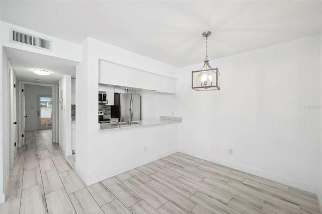 3102 W Horatio St Unit 13, Tampa, FL 33609 - kitchen with stainless steel appliances, wood tiled floors, white cabinetry, pendant lighting, and tasteful backsplash