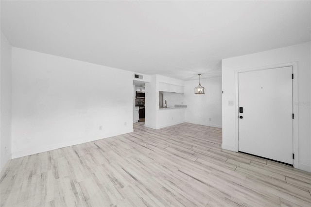3102 W Horatio St Unit 13, Tampa, FL 33609 - unfurnished living room featuring light wood-style flooring, a chandelier, and baseboards