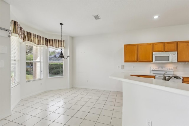 3311 Stonebridge Trl, Valrico, FL 33596 - kitchen with white appliances, light countertops, decorative light fixtures, brown cabinets, and light tile patterned floors