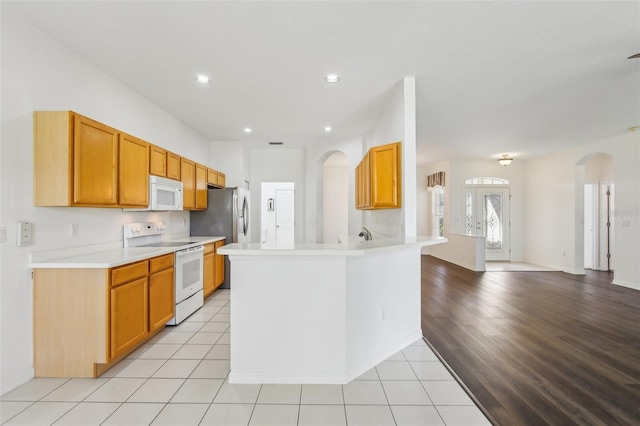 3311 Stonebridge Trl, Valrico, FL 33596 - kitchen featuring white appliances, arched walkways, light countertops, a peninsula, and recessed lighting