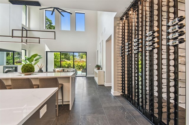 entrance foyer with plenty of natural light, baseboards, a towering ceiling, and dark tile patterned floors