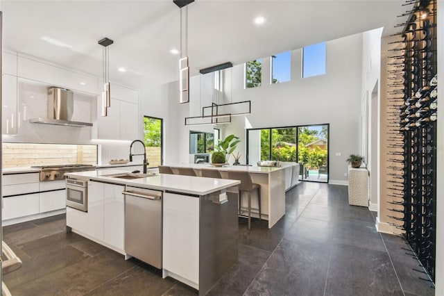 kitchen featuring a sink, wall chimney exhaust hood, a kitchen island with sink, modern cabinets, and white cabinets