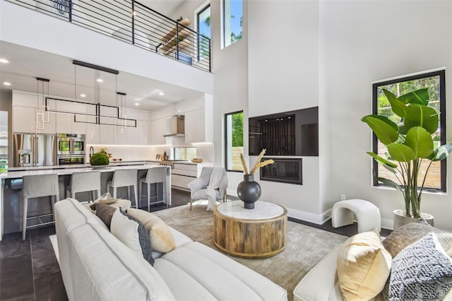 living area with a high ceiling, plenty of natural light, recessed lighting, and baseboards