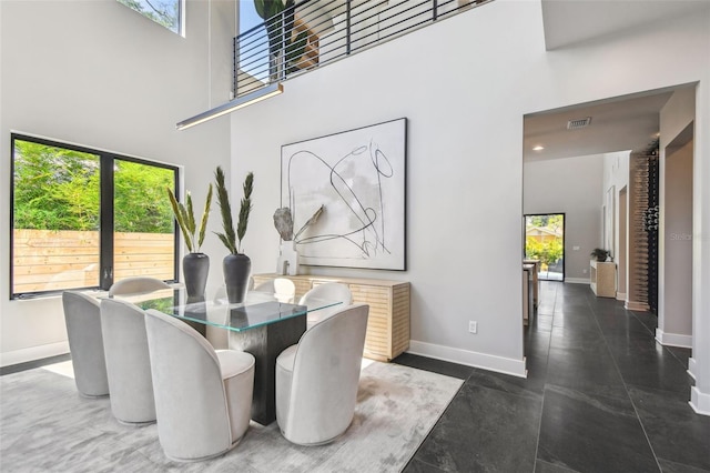 dining room with a towering ceiling, baseboards, and plenty of natural light