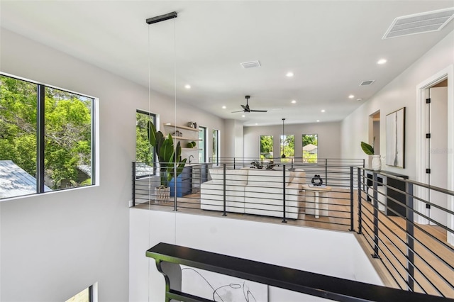 hall featuring plenty of natural light, recessed lighting, and an upstairs landing