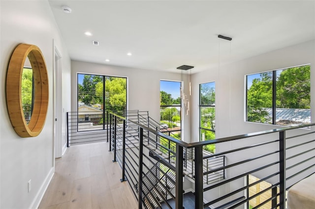 hall featuring an upstairs landing, baseboards, light wood finished floors, and recessed lighting