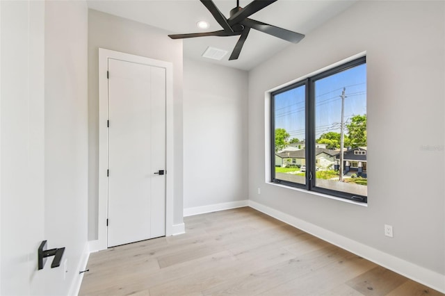 empty room with light wood-style flooring, a ceiling fan, and baseboards