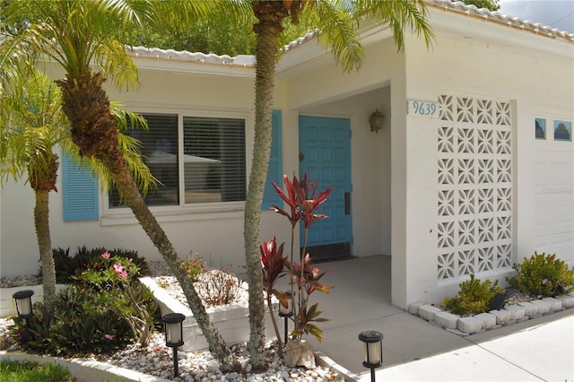 9639 Mainlands Blvd E, Pinellas Park, FL 33782 - doorway to property featuring stucco siding and a garage