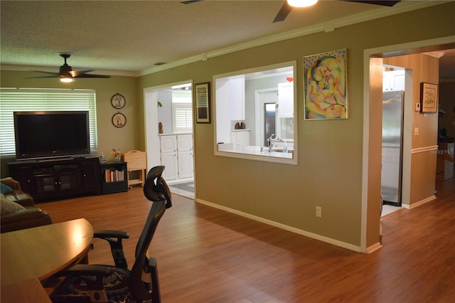 9639 Mainlands Blvd E, Pinellas Park, FL 33782 - living room with a ceiling fan, ornamental molding, wood finished floors, baseboards, and a textured ceiling