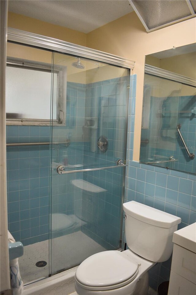 9639 Mainlands Blvd E, Pinellas Park, FL 33782 - bathroom with toilet, a stall shower, vanity, and tile walls