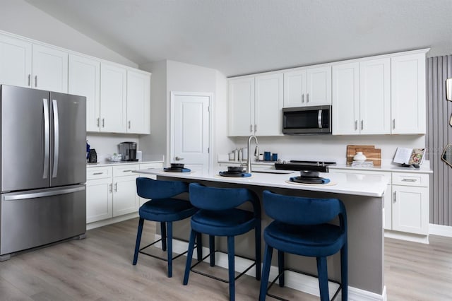 6236 SW 95th Pl, Ocala, FL 34476 - kitchen with appliances with stainless steel finishes, vaulted ceiling, light wood-style floors, light countertops, and a kitchen island with sink