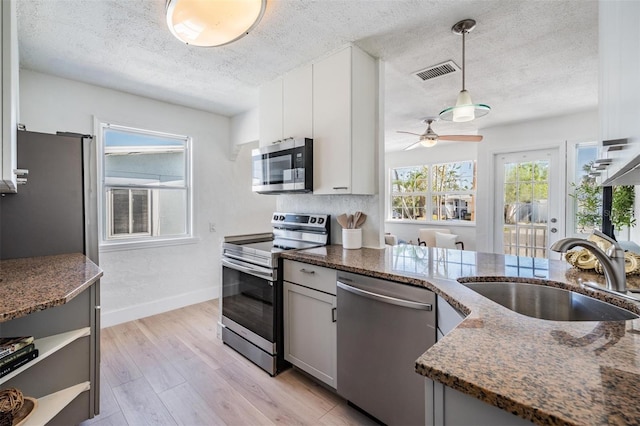 13304 2nd St E, Madeira Beach, FL 33708 - kitchen featuring stainless steel appliances, a sink, dark stone countertops, ceiling fan, and baseboards