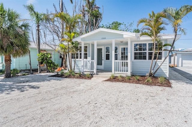 13304 2nd St E, Madeira Beach, FL 33708 - view of front of house featuring a porch, driveway, and a garage