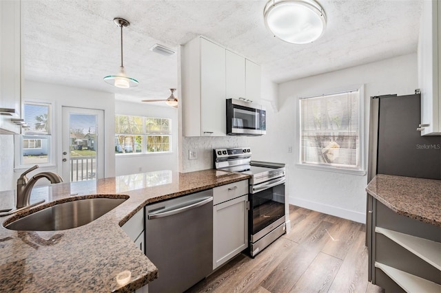 13304 2nd St E, Madeira Beach, FL 33708 - kitchen with appliances with stainless steel finishes, a sink, light wood-style floors, dark stone counters, and a textured ceiling