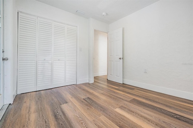 13304 2nd St E, Madeira Beach, FL 33708 - unfurnished bedroom with wood finished floors, a closet, and baseboards