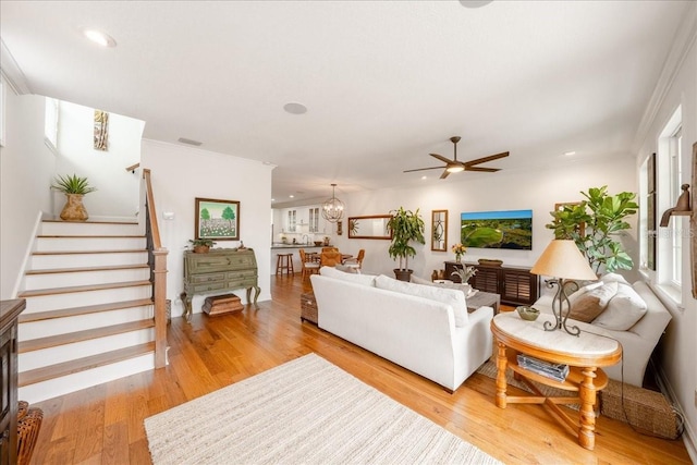 living room featuring ceiling fan, stairway, light wood-style floors, recessed lighting, and crown molding