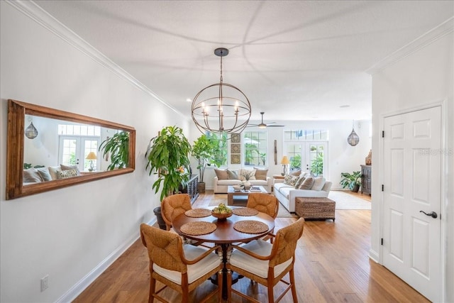 dining space with crown molding, wood finished floors, baseboards, and a chandelier