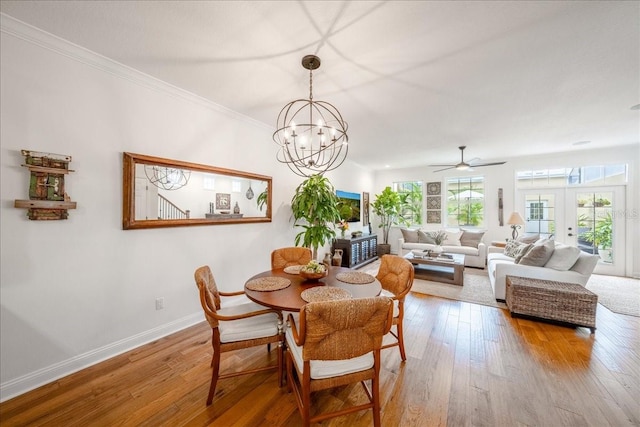 dining space with wood-type flooring, baseboards, a chandelier, crown molding, and a ceiling fan