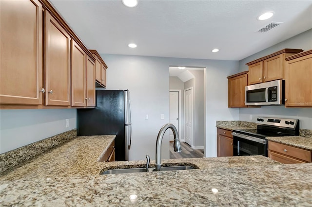 1107 Seminole Sky Dr, Ruskin, FL 33570 - kitchen with appliances with stainless steel finishes, a sink, light stone counters, recessed lighting, and brown cabinetry
