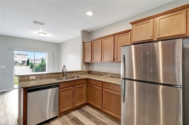 1107 Seminole Sky Dr, Ruskin, FL 33570 - kitchen featuring stainless steel appliances, a sink, light wood-style floors, a peninsula, and light stone countertops