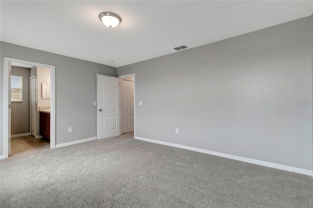 1107 Seminole Sky Dr, Ruskin, FL 33570 - unfurnished bedroom with light carpet, baseboards, and ensuite bathroom