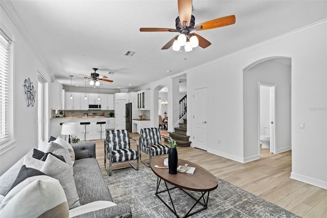 16206 Nottingham Park Way, Tampa, FL 33647 - living area with arched walkways, a ceiling fan, light wood-style floors, ornamental molding, and stairway