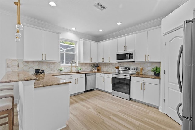 16206 Nottingham Park Way, Tampa, FL 33647 - kitchen with stainless steel appliances, a sink, a peninsula, crown molding, and white cabinets