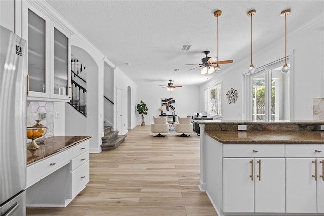 16206 Nottingham Park Way, Tampa, FL 33647 - kitchen with freestanding refrigerator, arched walkways, light wood finished floors, white cabinetry, and ornamental molding