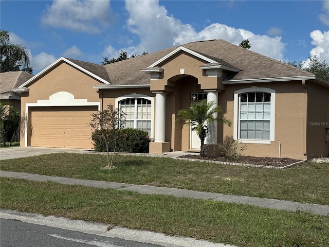 view of front of property featuring stucco siding, an attached garage, a front lawn, and driveway
