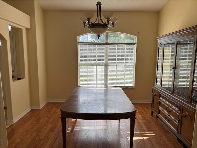 dining area with a chandelier, dark wood-type flooring, and baseboards