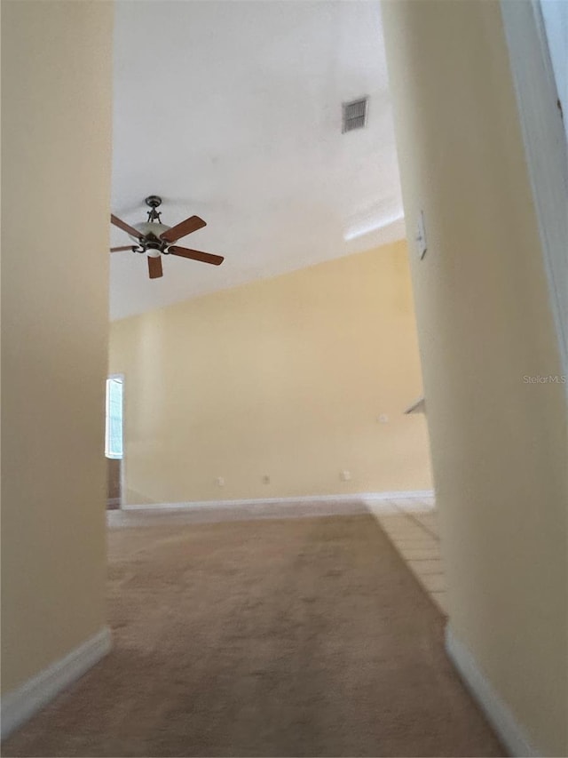 spare room featuring ceiling fan, light colored carpet, and baseboards