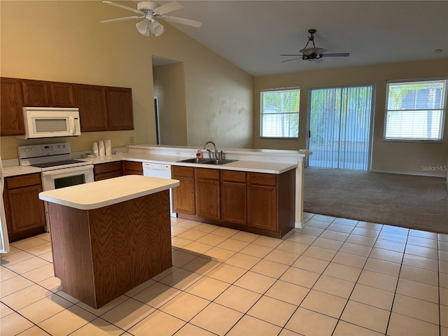 kitchen featuring white appliances, a sink, ceiling fan, a peninsula, and lofted ceiling