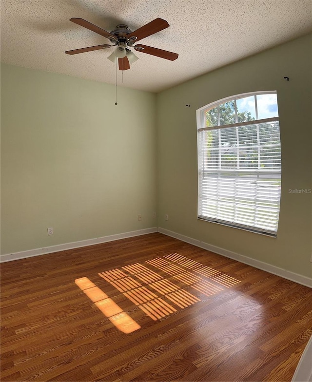 unfurnished room with a ceiling fan, wood finished floors, baseboards, and a textured ceiling