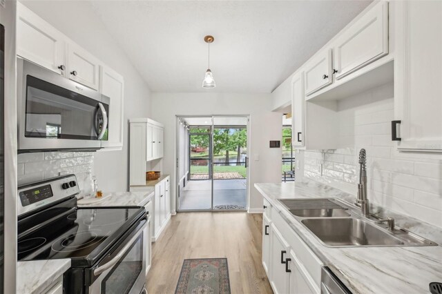 kitchen featuring appliances with stainless steel finishes, a sink, light wood-style floors, and white cabinets