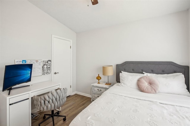bedroom featuring wood finished floors, an office area, baseboards, vaulted ceiling, and a ceiling fan