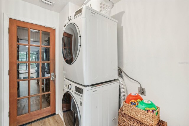 washroom featuring stacked washing machine and dryer and light wood finished floors