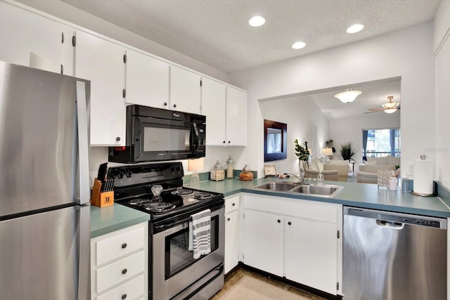 1390 Oak Hill Dr Unit 206, Dunedin, FL 34698 - kitchen featuring stainless steel appliances, a sink, white cabinetry, a textured ceiling, and dark countertops