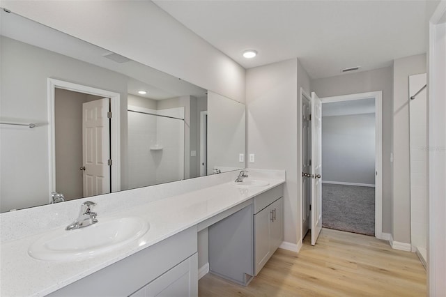 full bath with a shower, wood finished floors, double vanity, baseboards, and recessed lighting