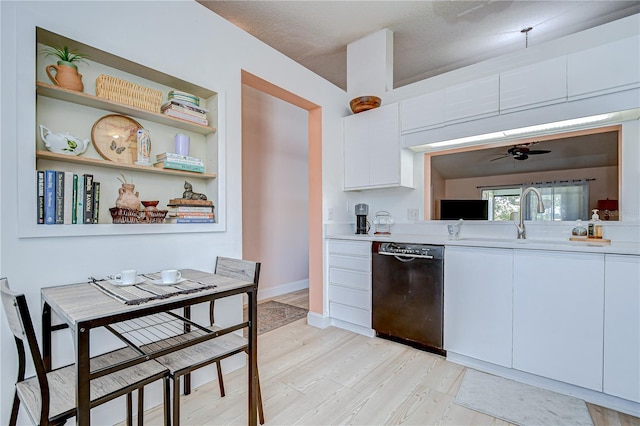 2139 Elm St Unit 308, Dunedin, FL 34698 - kitchen with black dishwasher, light countertops, white cabinets, a sink, and light wood-style flooring